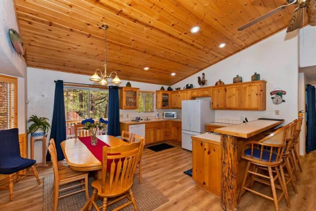 una cocina con armarios de madera, mesa y sillas en Cozy Adorable Cabin / Scenic Outdoor dining area en Big Bear City