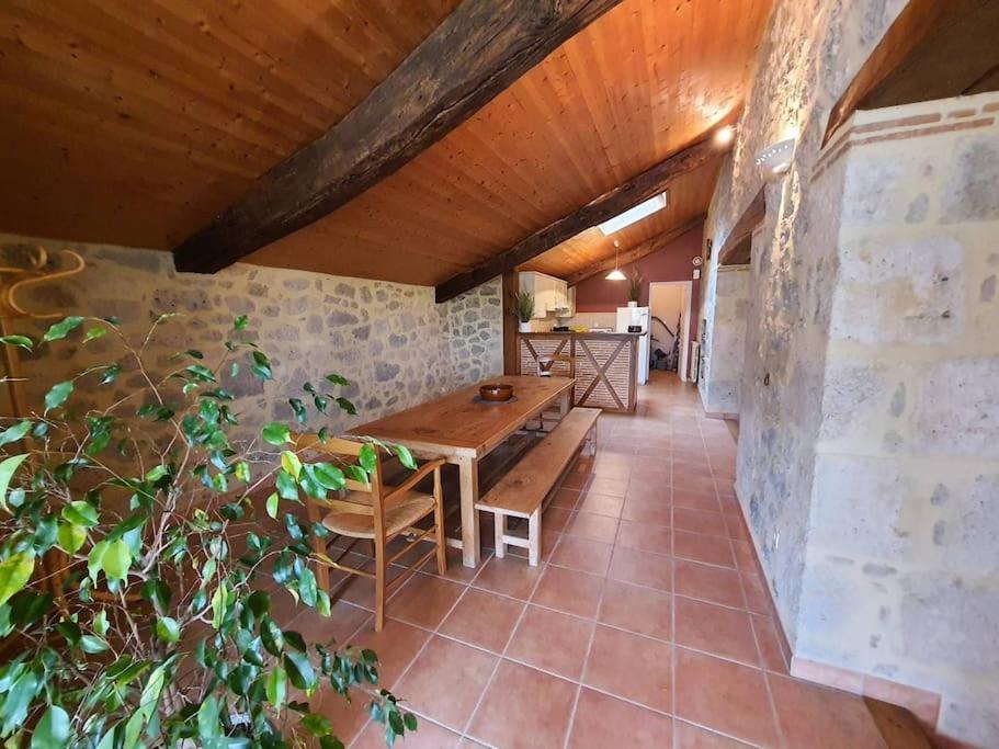 a dining room with a table and a stone wall at Location à Lannes - Clévacances 3 clés in Lannes