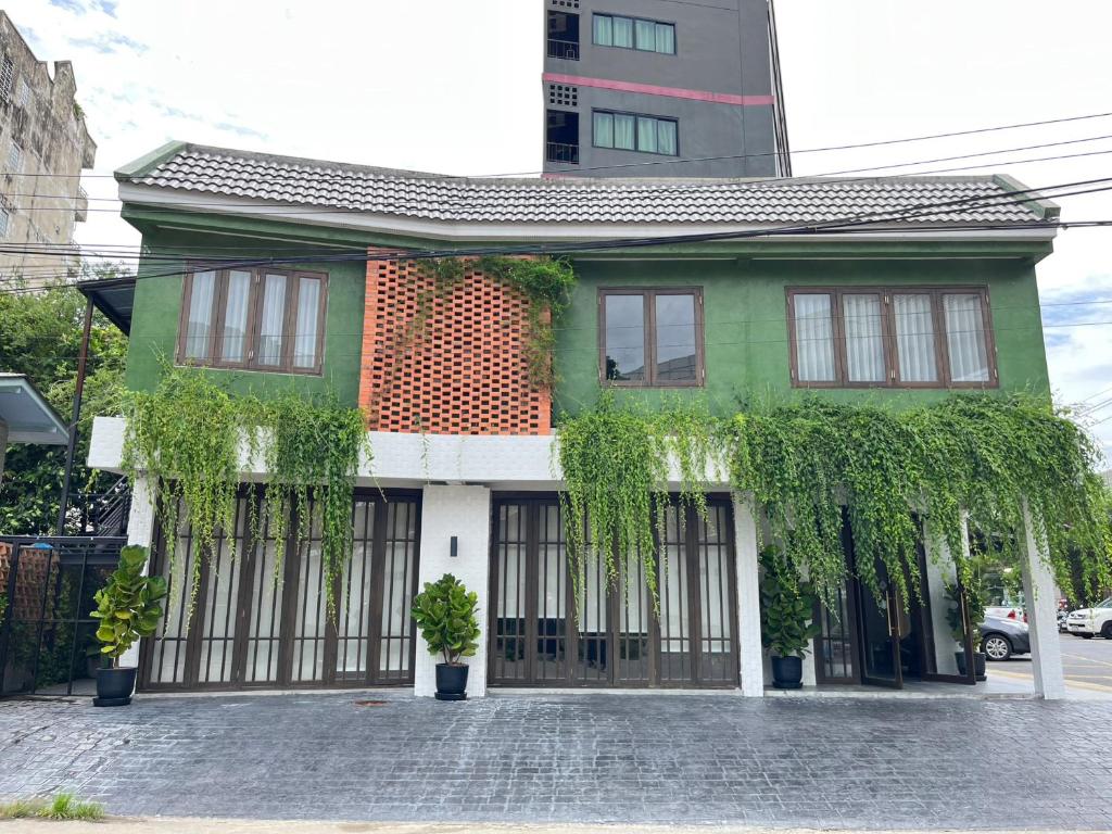 una casa verde y blanca con plantas. en Homie Non - โฮมมี่ นนท์ en Ban Bang Khwang