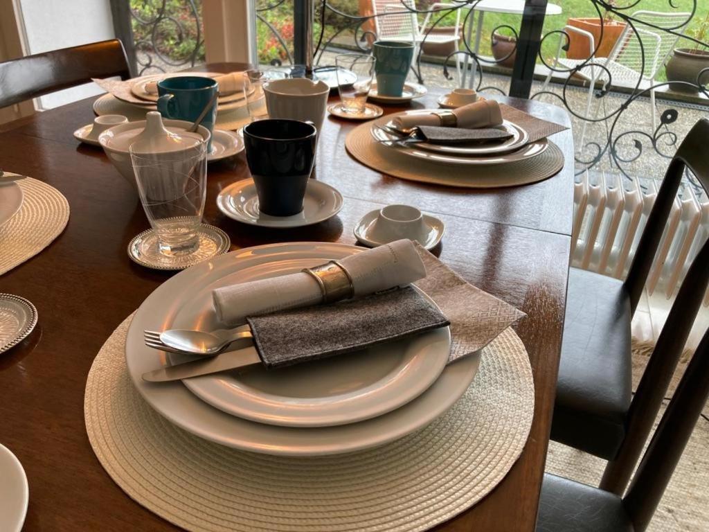 a wooden table with plates and silverware on it at Privates Zimmer & Bad in Aalen/Unterkochen in Unterkochen