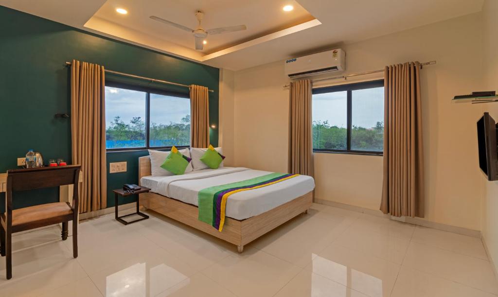 a bedroom with a bed and a desk and windows at Treebo Trend Tulip Comfort in Pune