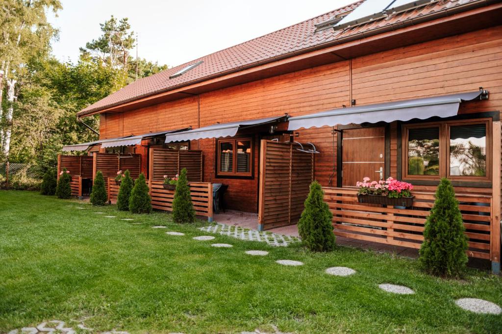 a wooden house with a lawn in front of it at Pokoje Na Wydmie in Dziwnówek