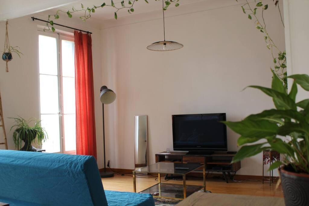 un salon avec un canapé bleu et une télévision dans l'établissement Noailles experience - Centre Marseille /Vieux-Port, à Marseille