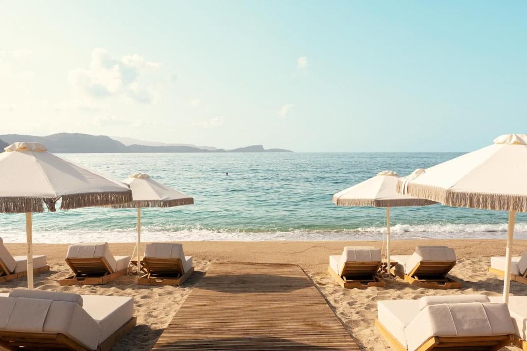 einen Strand mit Liegestühlen und Sonnenschirmen und dem Meer in der Unterkunft Enjoy Lichnos Bay Village, Camping, Hotel and Apartments in Parga