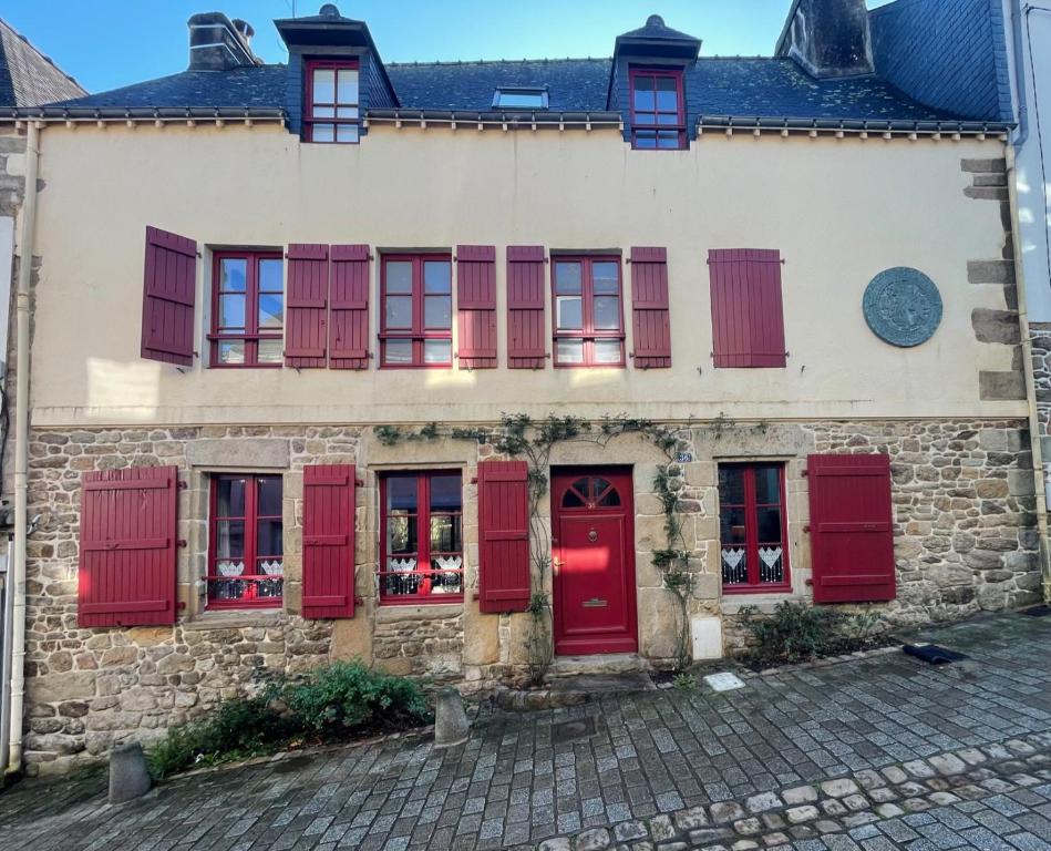 - un vieux bâtiment en pierre avec des portes et des fenêtres rouges dans l'établissement Maison de caractère ST GOUSTAN, à Auray