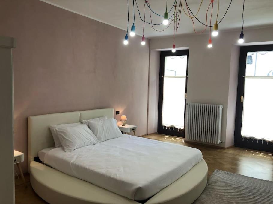 1 Schlafzimmer mit einem großen weißen Bett und 2 Fenstern in der Unterkunft Casa in centro Domodossola self check in in Domodossola