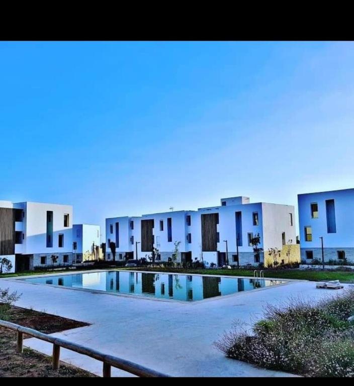 uma piscina em frente a alguns edifícios brancos em Bel Appartement Tamourit Agadir em Agadir