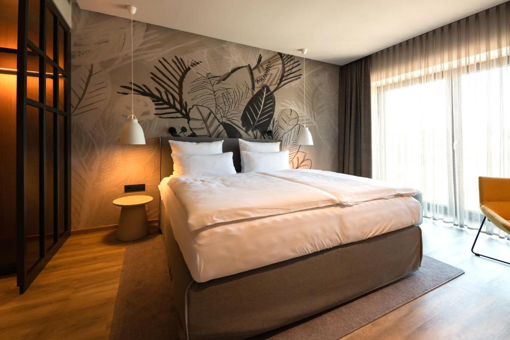 a bedroom with a large bed and a wall with plants at Thöles Hotel Bücken in Bücken