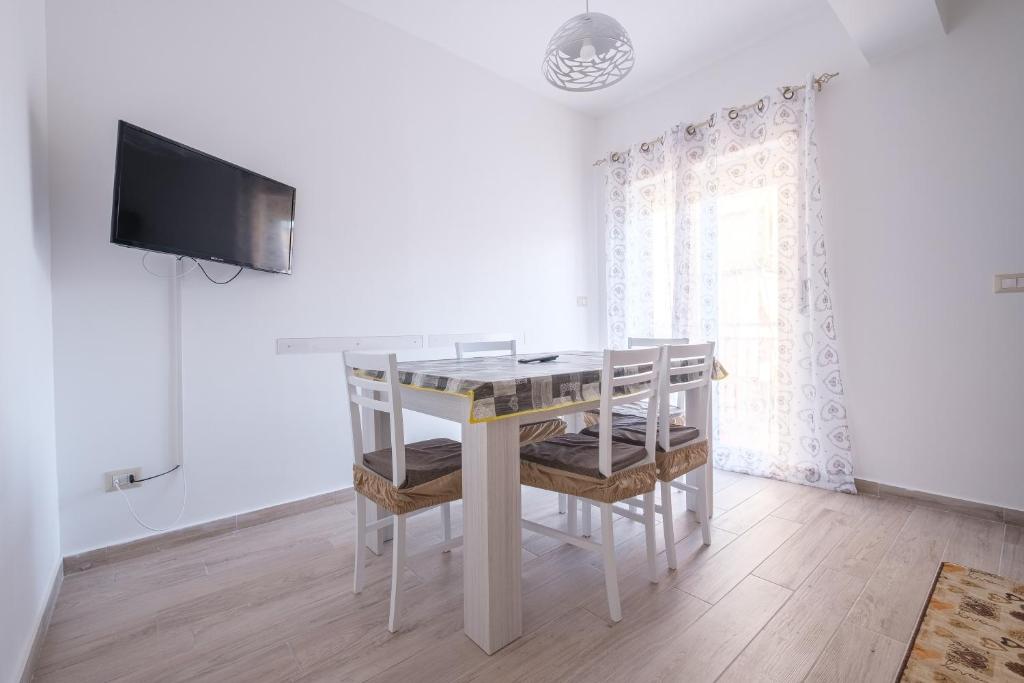 a white dining room with a table and a tv at Damilhouse 4 in Messina