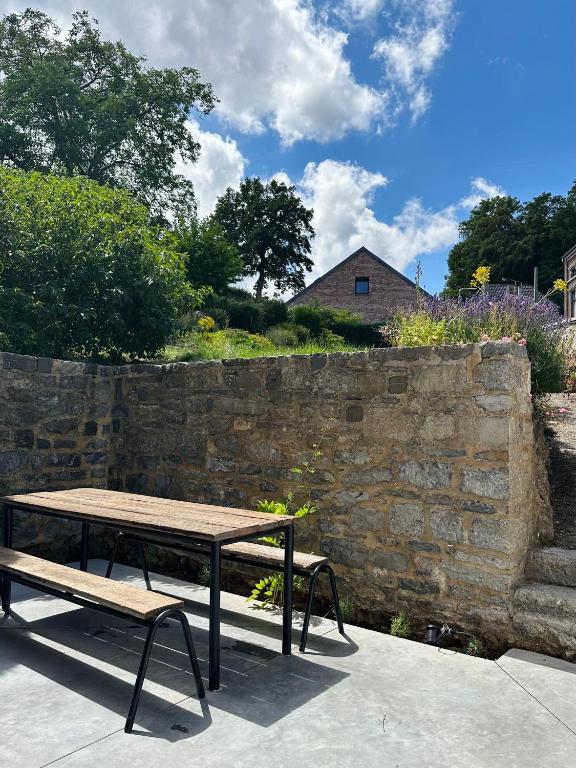 a picnic table and bench next to a stone wall at Maison Comtale in Rochefort