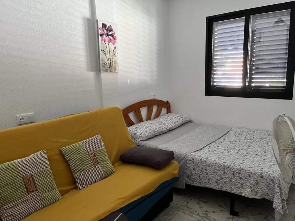 1 dormitorio con cama y sofá amarillo en Apartment with Outdoor Pool and Air Conditioning in Cabo Roig, en Cabo Roig