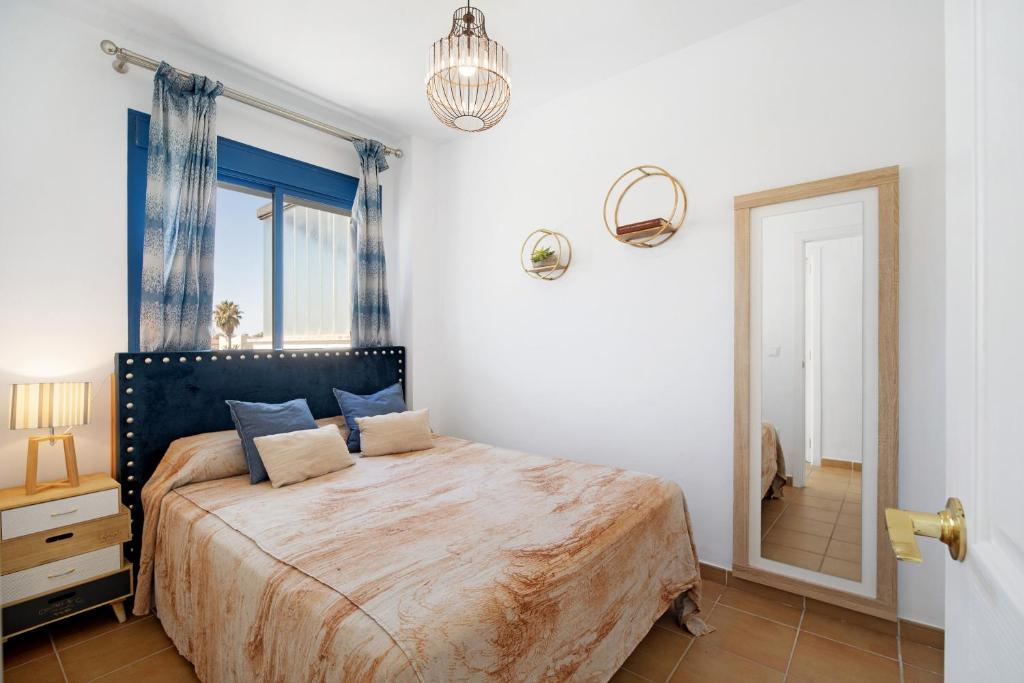 1 dormitorio con 1 cama grande y espejo en Casa en Costa Ballena, en Rota