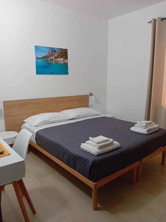 ein Schlafzimmer mit einem Bett mit einer blauen Decke und einem Tisch in der Unterkunft Eliseo's rooms in Triei