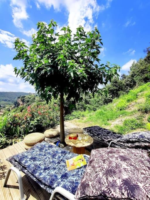 une table et des chaises avec un arbre sur une terrasse dans l'établissement Maison vue sur le village, à Cotignac