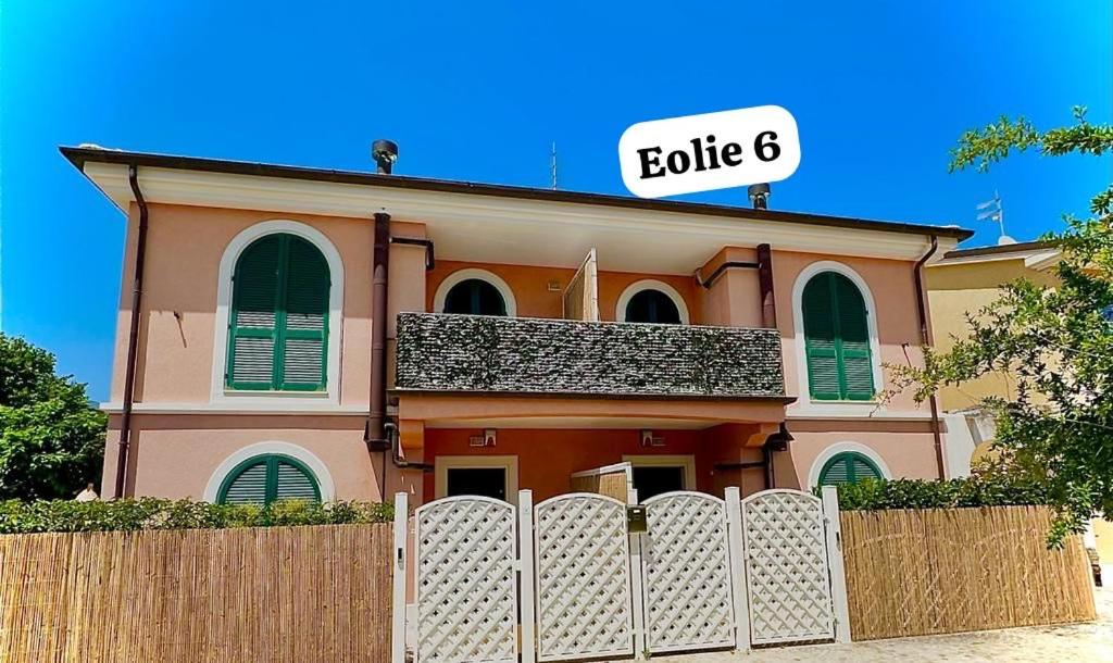 uma casa cor-de-rosa com uma vedação à frente. em Conero Casa - Marcelli di Numana in Piazzale Eolie 6 em Marcelli