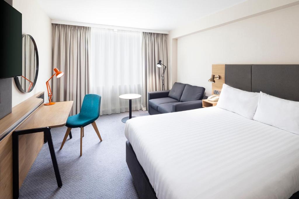 une chambre d'hôtel avec un lit et une chaise dans l'établissement Holiday Inn Coventry M6, J2, an IHG Hotel, à Coventry