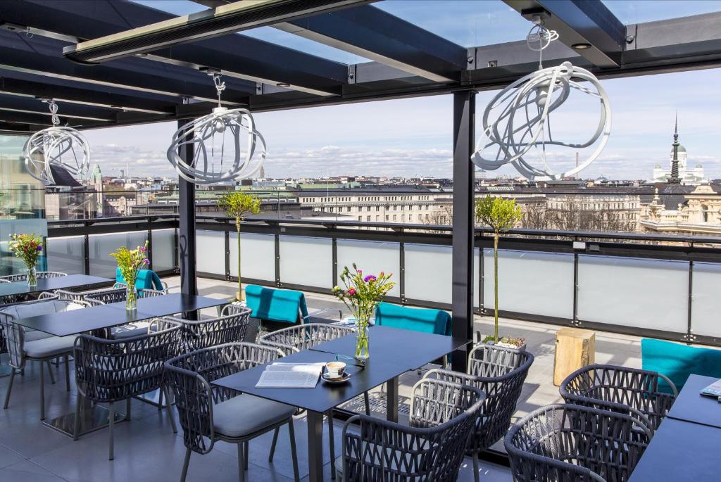 a restaurant with tables and chairs and a view of the city at Hotel Klaus K in Helsinki