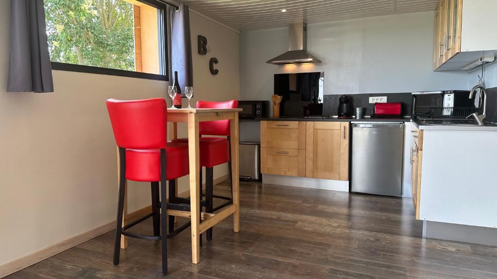 una cocina con sillas rojas y una mesa. en Les gîtes du Canal du midi - Gîte Bois & Cailloux, en Montgaillard-Lauragais