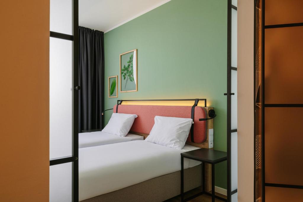 a bedroom with a bed with white sheets and green walls at Campanile Krakow South in Krakow