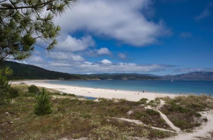 a beach with people on the sand and water at O Aserradero in Finisterre