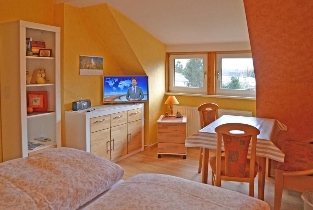 a bedroom with a bed and a table and a tv at Pension Pusch Inh_ Ursula Pusch in Guben