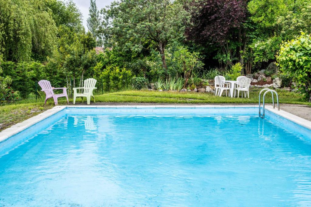 a swimming pool with two chairs and a table at Logis Hôtel La crémaillère in Hagetmau