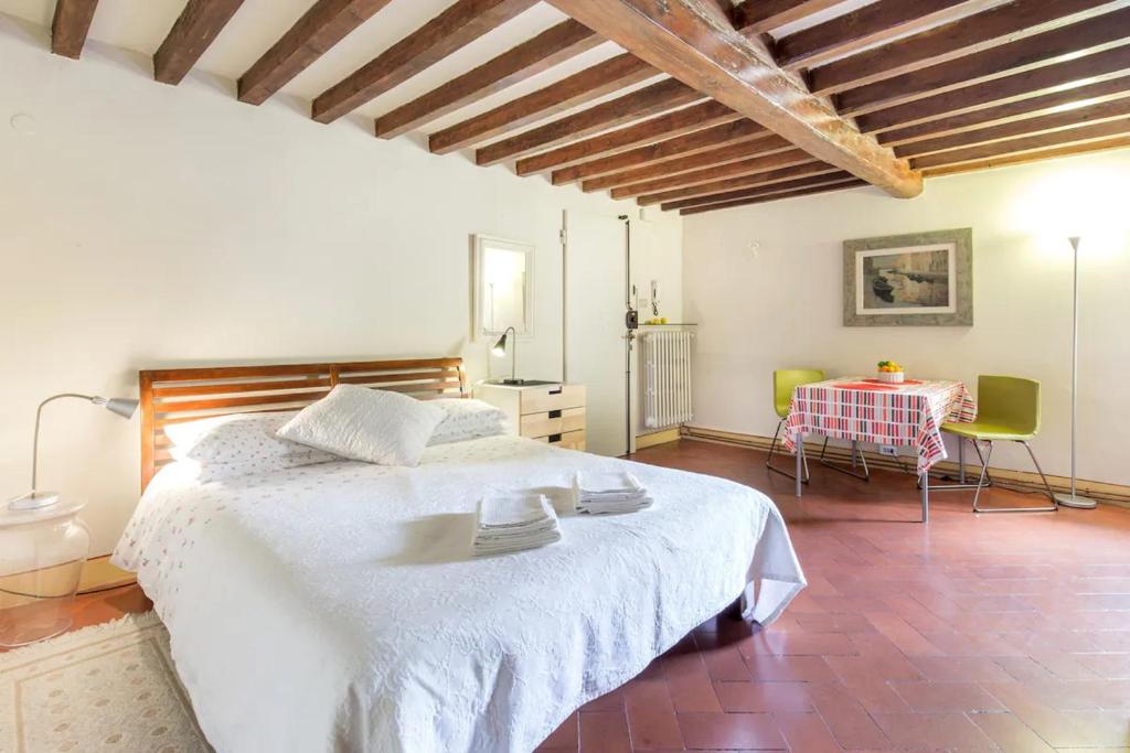 a bedroom with a large white bed and a table at Spacious studio apt (n.2) Ancient Palazzo in Florence