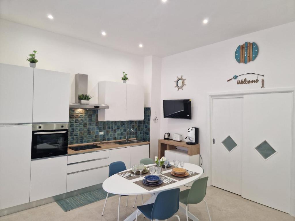 eine Küche mit weißen Schränken sowie einem Tisch und Stühlen in der Unterkunft ondina house in Giardini-Naxos