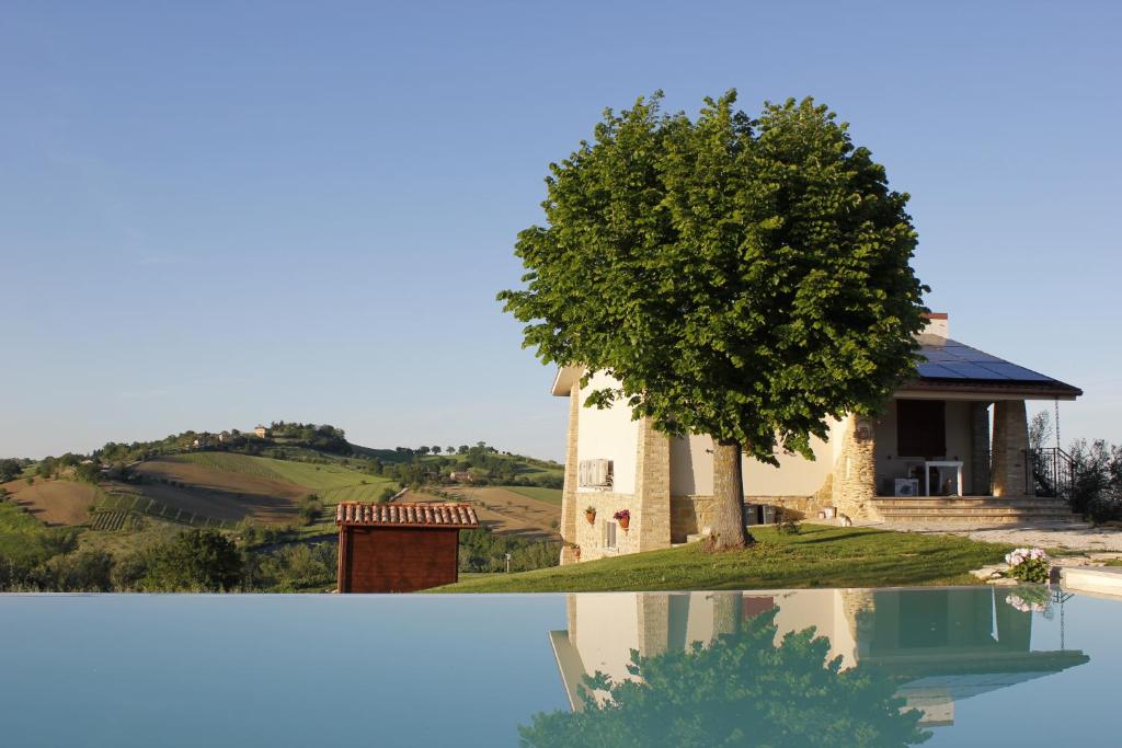 un bâtiment et un arbre à côté d'une maison dans l'établissement Villa Edelia, à Mondavio