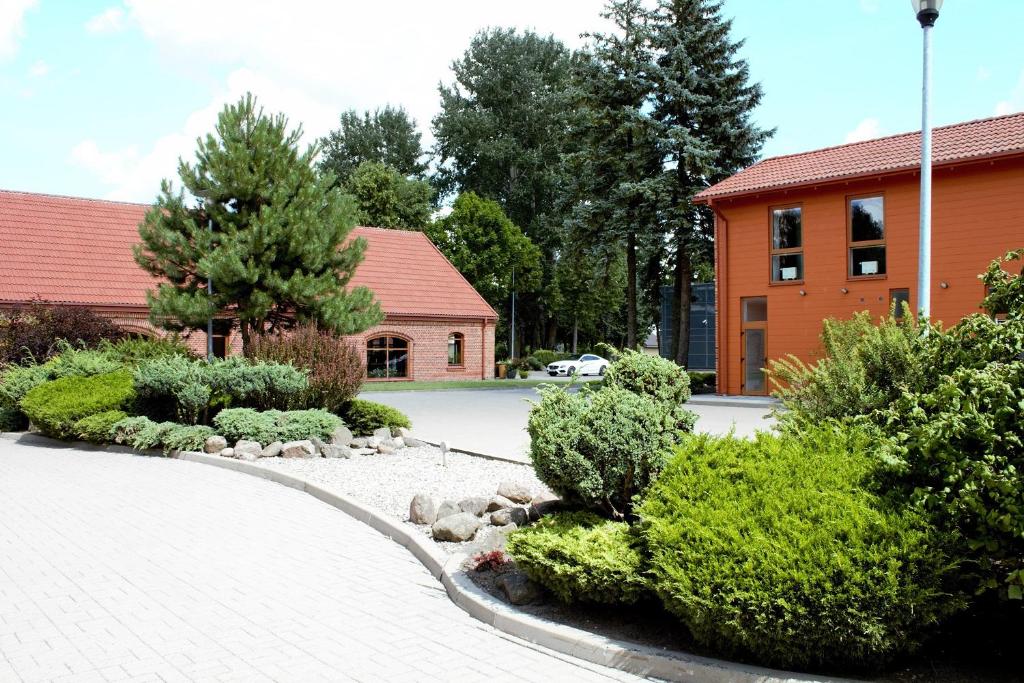 un jardín con arbustos y árboles y un edificio en LUNA Marijampole en Marijampolė