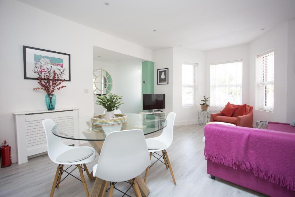 uma sala de estar com uma mesa de vidro e cadeiras brancas em Oceans 12a Shelley Lofts, sleeps 4 em Worthing