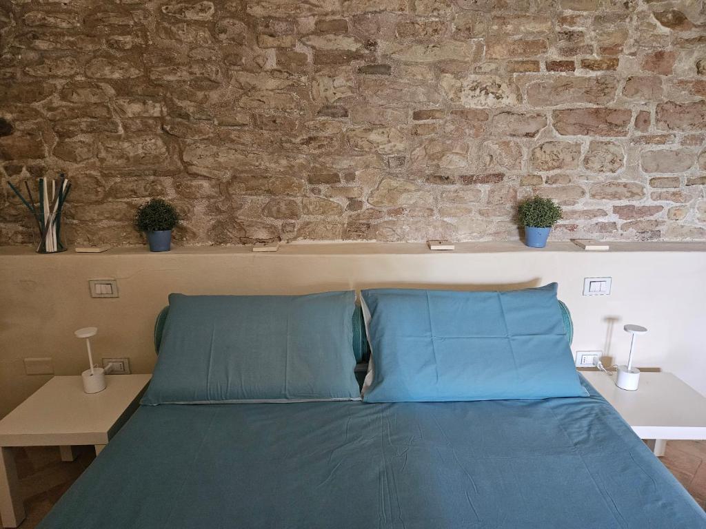 łóżko z niebieskimi poduszkami przed ścianą z cegły w obiekcie Agriturismo Molleone w mieście Cagli