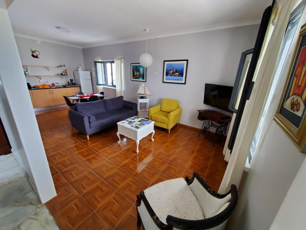 a living room with a blue couch and yellow chairs at Pousada da Vila in Vila Franca do Campo