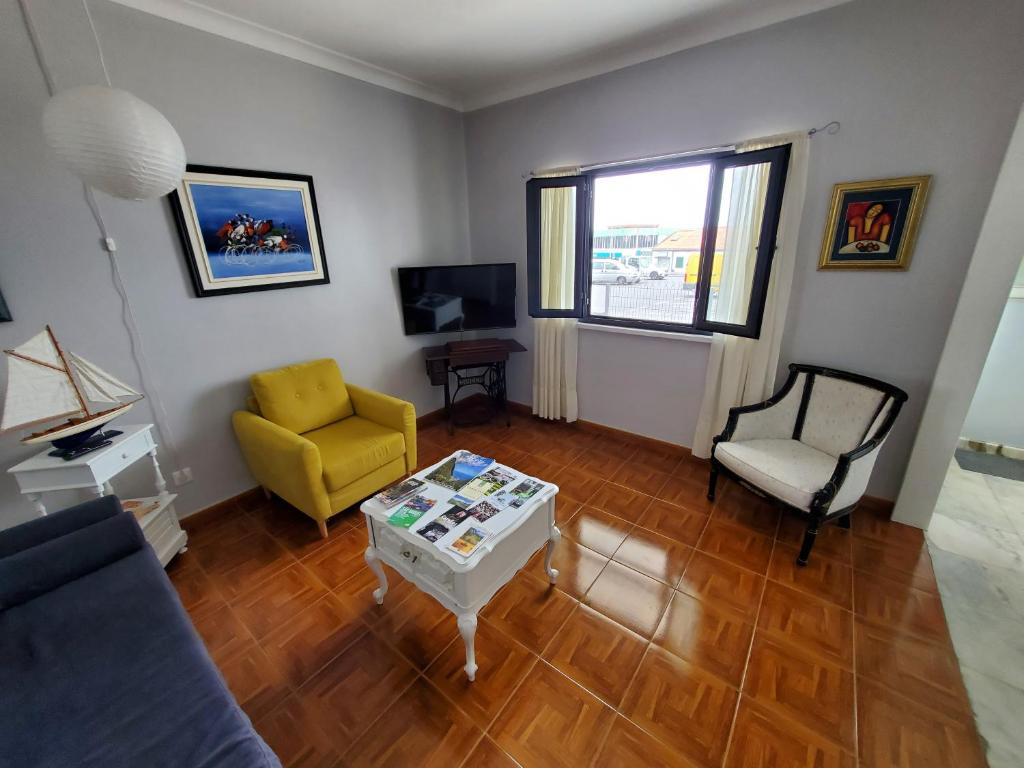 a living room with a yellow chair and a table at Pousada da Vila in Vila Franca do Campo