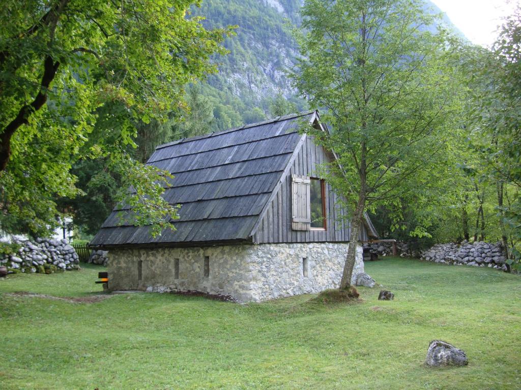a stone house with a black roof in a field at House Pod Lipo in Trenta