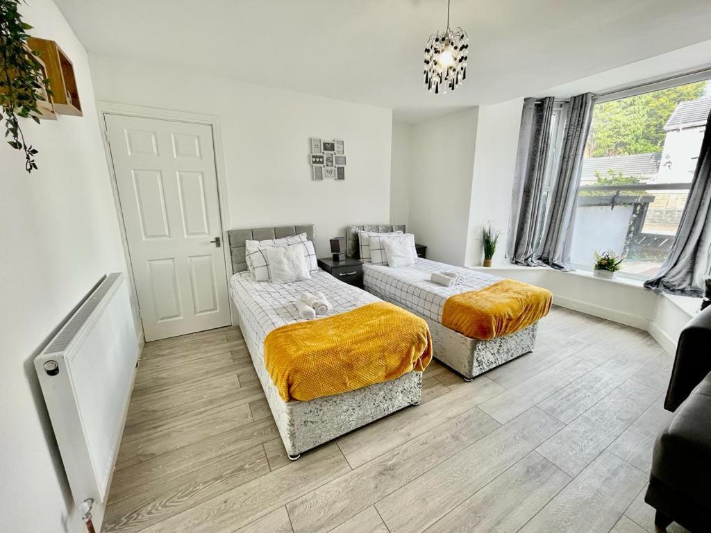 a bedroom with two beds and a chandelier at Cosy 1-Bedroom Apartment Briton Ferry, Neath Port Talbot in Briton Ferry