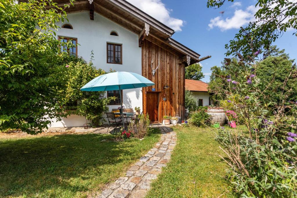 a house with a blue umbrella in the yard at Landhaus Gustl in Chieming