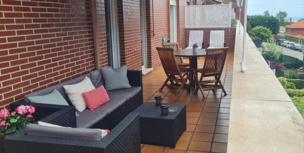 a patio with a couch and a table on a balcony at Piso "Al Norte" Luanco Terraza Parking WI-FI in Luanco