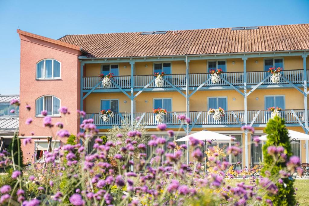 un bâtiment avec des fleurs violettes devant lui dans l'établissement JUFA Hotel Vulkanland, à Gnas
