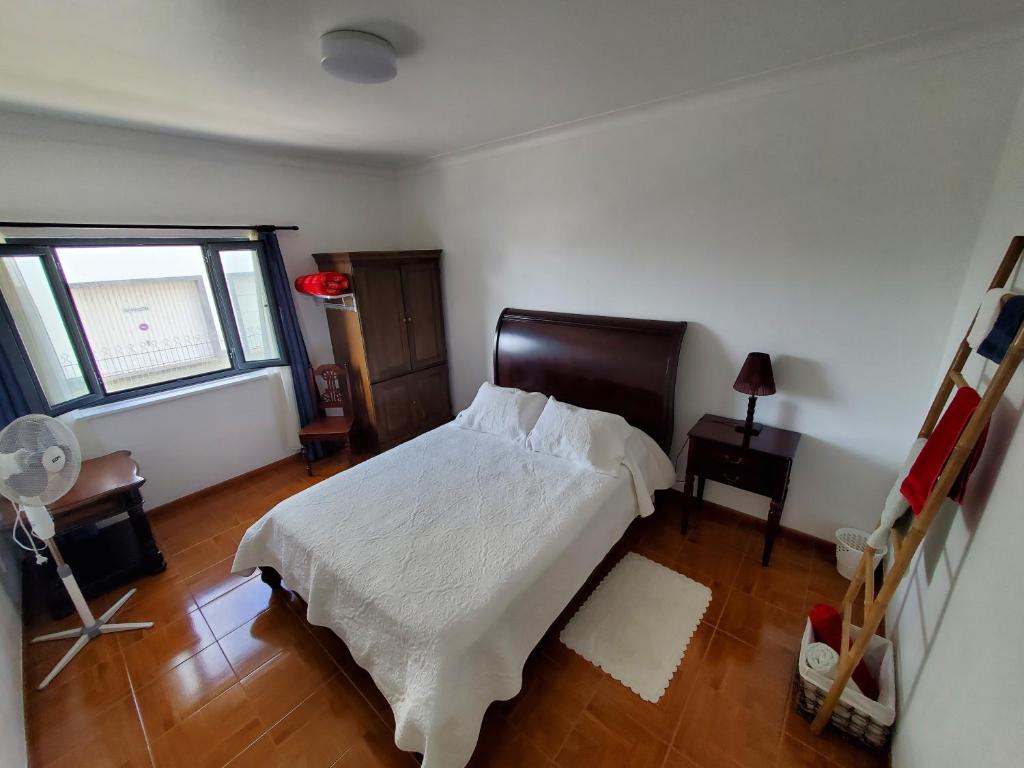 a bedroom with a bed with white sheets and a window at Pousada da Vila in Vila Franca do Campo