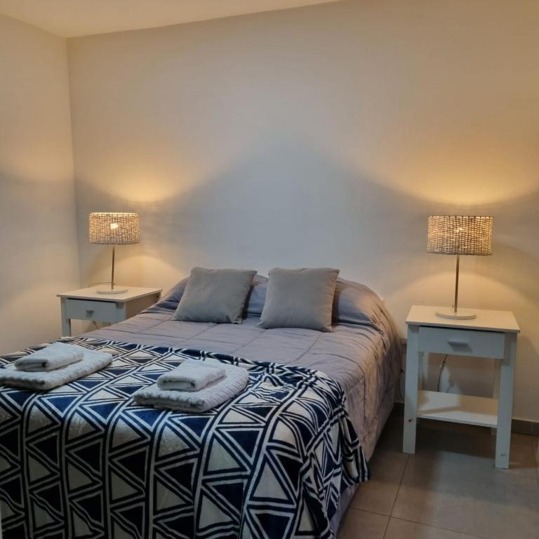 a bedroom with a bed and two lamps on two tables at Happy Guest Apart 53 in Ushuaia