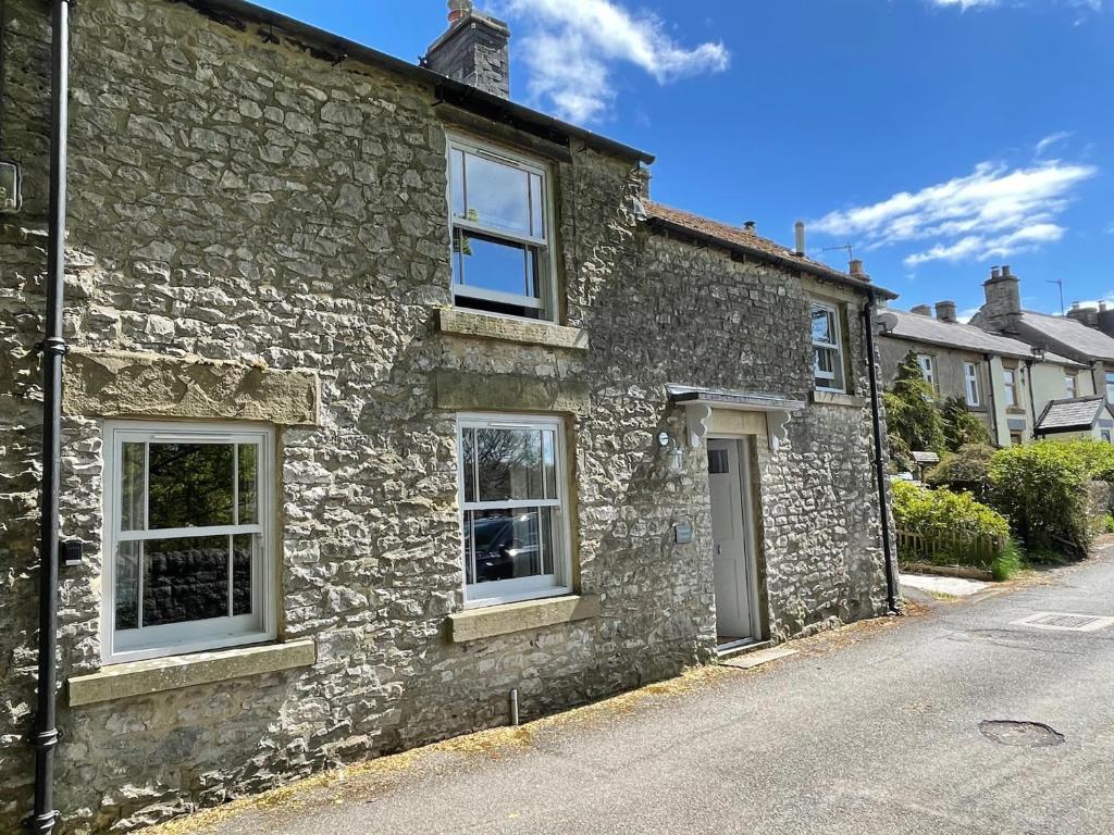 an old stone house with white windows on a street at Weavers Cottage, Sleeps 6, outside terrace in Buxton