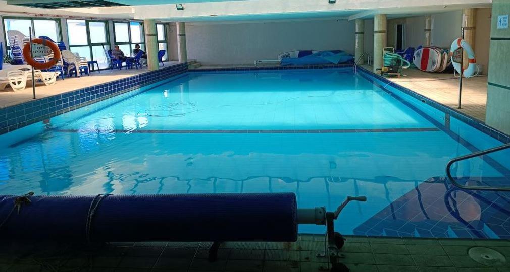 a large swimming pool with blue water in a building at Pool, Sauna, Gym & Spa @ Beach-Front Apartment Hotel in Ashkelon