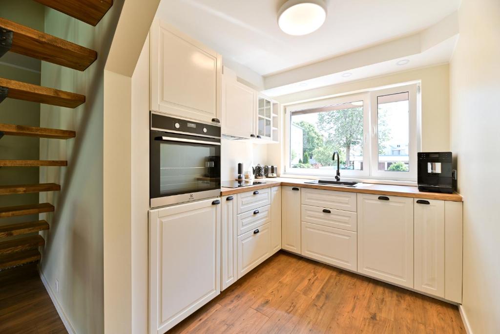 a kitchen with white cabinets and a window at Kuressaare Pikk Apartment in Kuressaare