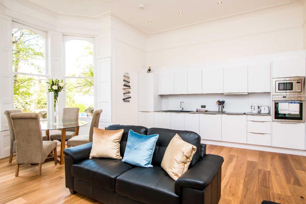 a living room with a black couch and a kitchen at Beaufort House Apartments from Your Stay Bristol in Bristol