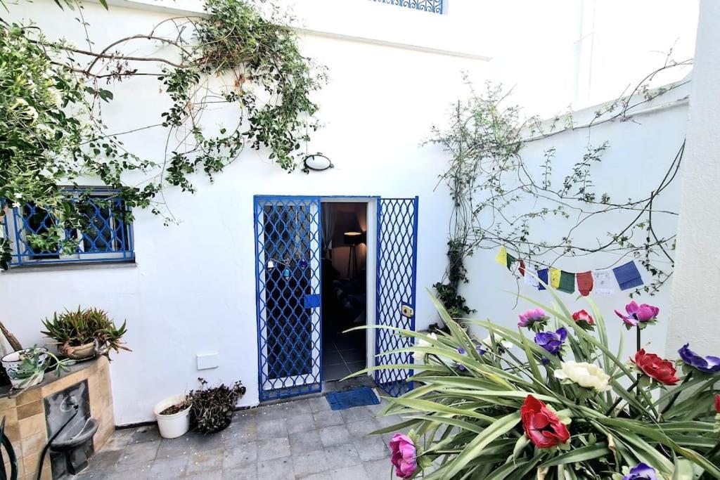 una casa blanca con una puerta azul y flores en La Maisonnette Turquoise, en Dar Mimoun Bey