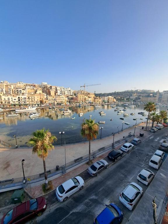 a parking lot with cars parked next to a harbor at B&S Accommodation Seafront Duplex Penthouse in Marsaskala