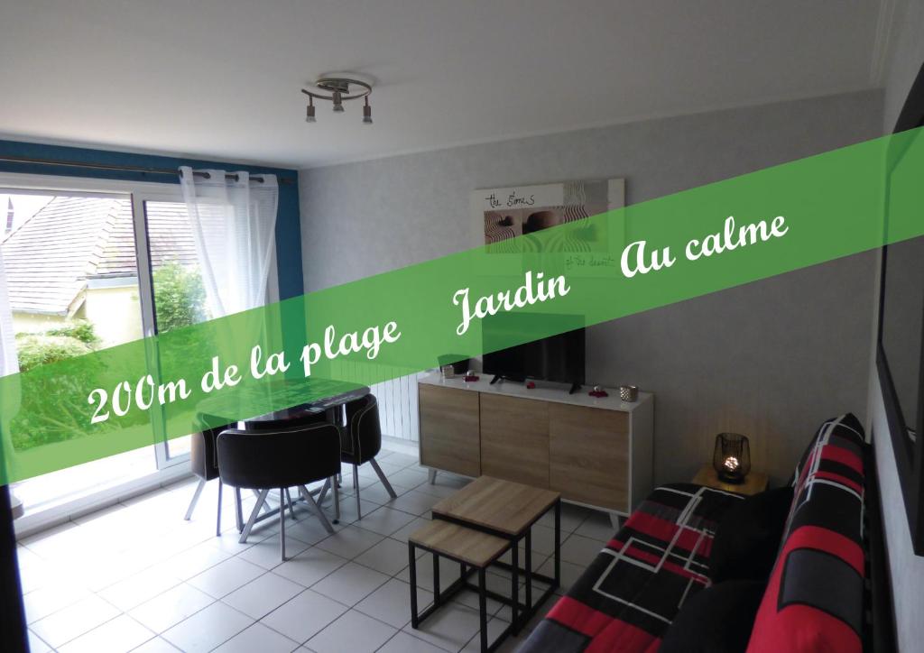 un salon avec une bannière verte sur le mur dans l'établissement Le VIP cabourg,200m de la plage et de la promenade Marcel Proust,600m du centre, agréable F2 en rez de jardin, à Cabourg