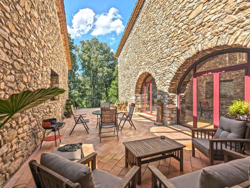 un patio al aire libre con mesas y sillas y un edificio de ladrillo en Can Carreres - Un lloc on desconnectar en família, en El Pasteral