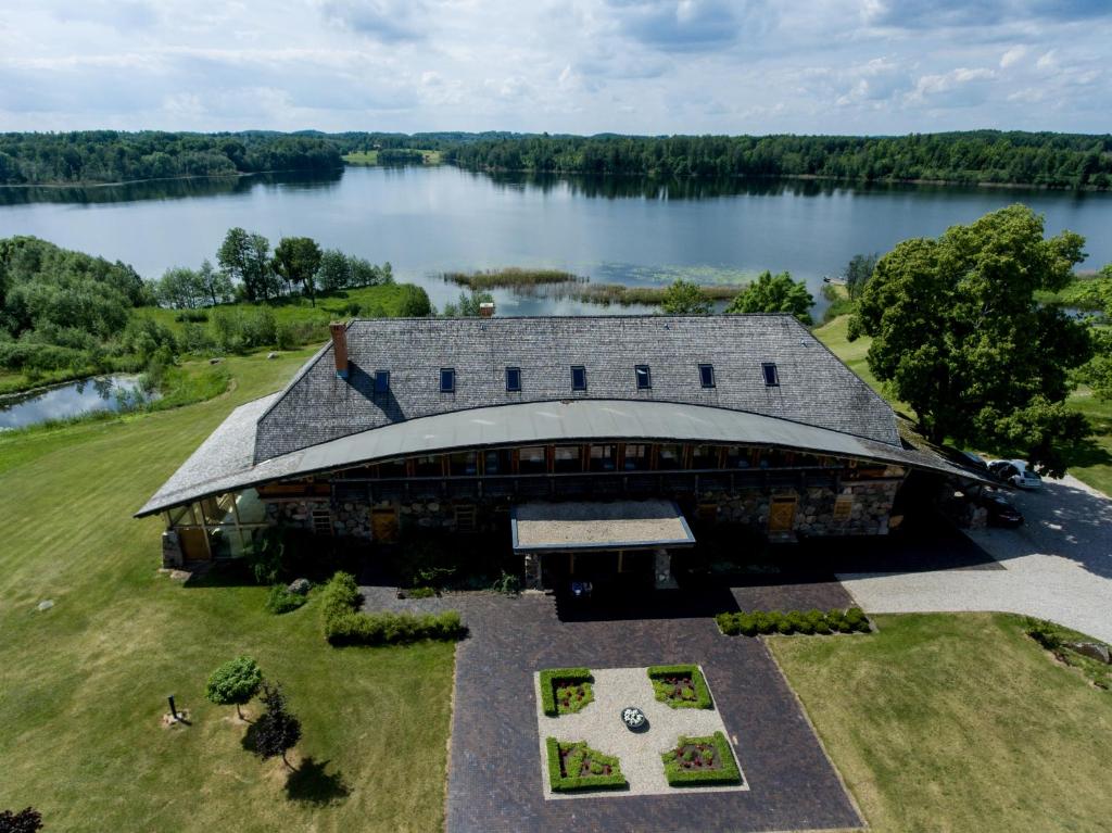 Žabičiūnai的住宿－Vasaknų dvaras，享有一座建筑的顶部景色,建筑背景是湖泊